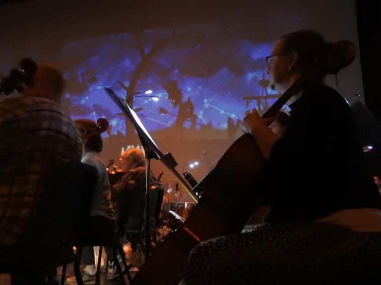 A snapshot from the concert showing an animated film playing behind an orchestra