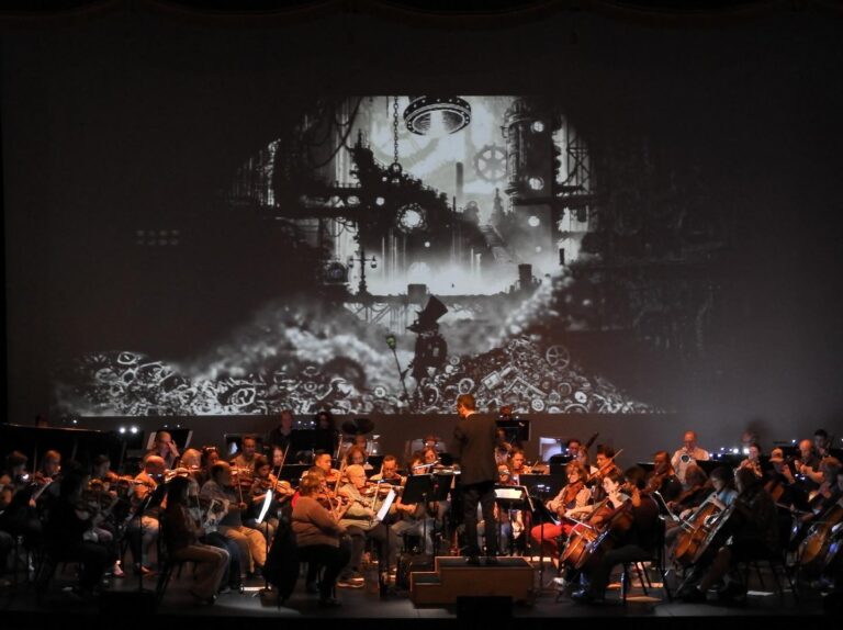 A snapshot from the concert showing an animated film playing behind an orchestra