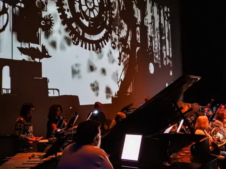 A snapshot from the concert showing an animated film playing behind an orchestra