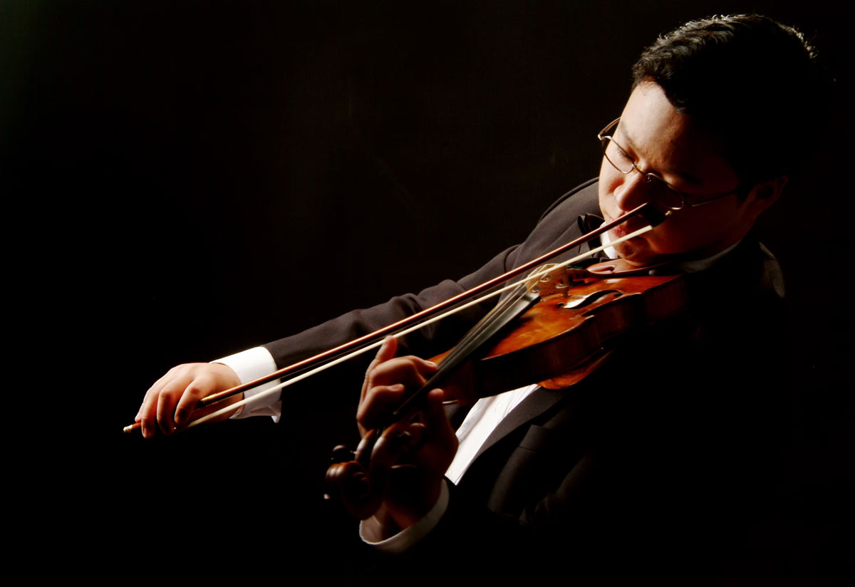 A man in a tuxedo plays violin passionately