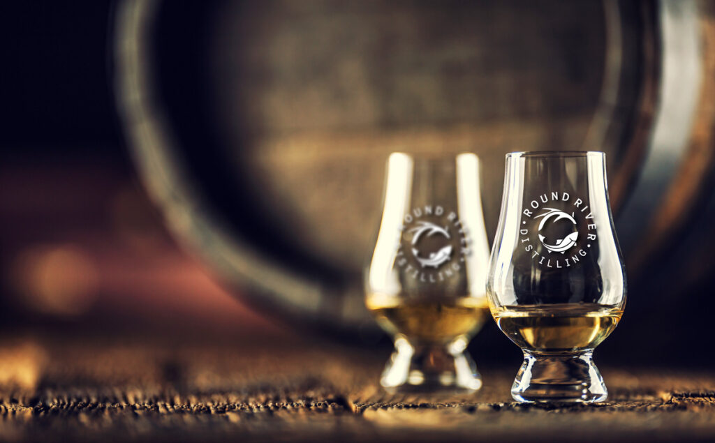 2 bourbon tasting glasses in front of a bourbon barrel