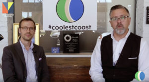 Two men seated for an interview with a coolestcoast logo in the background.