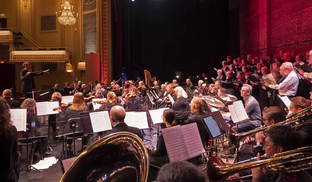 An orchestra and a chorus on a stage of a beautiful theater, shot from the side of the stage.